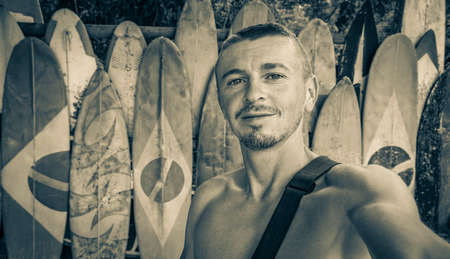 Black and white picture of a surfer tourist and traveler with surfboards with brazilian flag at the...