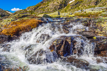 Amazing VeslehÃ¸dn mountain peak river and snow in summer by the Hydnefossen waterfall in Hemsedal Norway.の写真素材