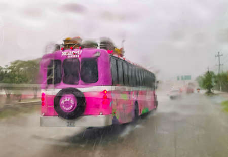 Playa del Carmen Mexico March 12, 2022 Pink Xcaret bus drives in heavy rain monsoon on the highway freeway Playa del Carmen in Quintana Roo Mexico.のeditorial素材