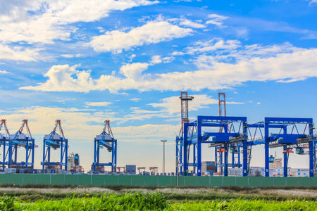 Industrial area cranes and red tower lighthouse with beautiful grassland and dike dyke nature seascape panorama in Imsum Geestland Cuxhaven Lower Saxony Germany.のeditorial素材