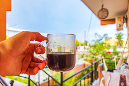 A glass of coffee in hand in the morning in tropical landscape in Playa del Carmen Mexico.の写真素材