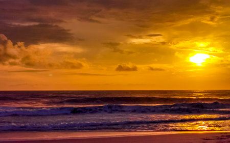 Beautiful stunning colorful and golden sunset in yellow orange red on beach and big wave panorama in tropical nature in Zicatela Puerto Escondido Oaxaca Mexico.の写真素材