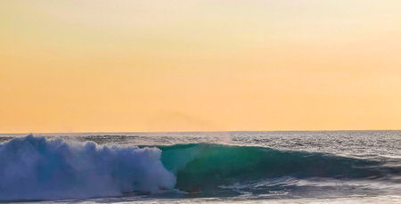 Beautiful stunning colorful and golden sunset in yellow orange red on beach and big wave panorama in tropical nature in Zicatela Puerto Escondido Oaxaca Mexico.の写真素材