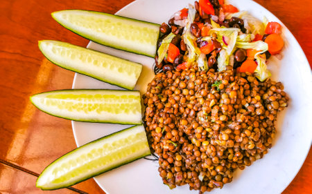 Delicious lentil dish lentil stew with beans vegetables cucumbers tomatoes onions and carrots on brown wooden table Hin in Playa del Carmen Mexico.の写真素材