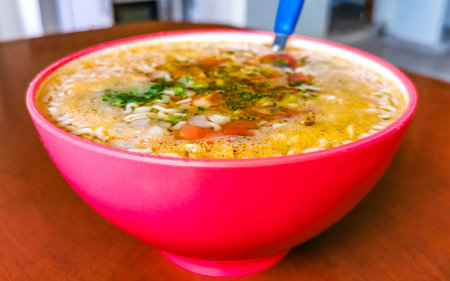 Noodle soup instant soup in pink bowl on brown wooden table background in Playa del Carmen Quintana...