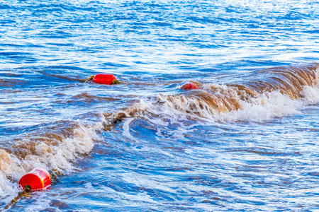 Beautiful blue and turquoise water waves ocean and yellow red orange buoy and ropes in the water of...