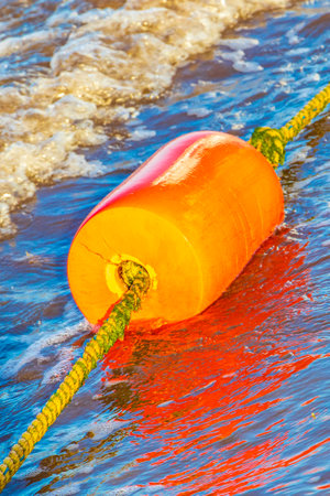 Beautiful blue and turquoise water waves ocean and yellow red orange buoy and ropes in the water of Playa del Carmen in Quintana Roo Mexico.の写真素材