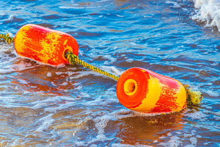 Beautiful blue and turquoise water waves ocean and yellow red orange buoy and ropes in the water of Playa del Carmen in Quintana Roo Mexico.の写真素材