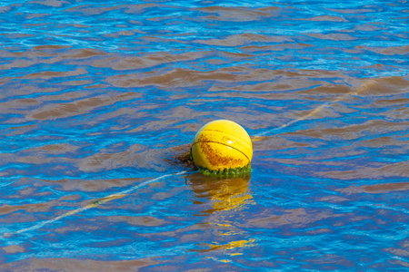 Beautiful blue and turquoise water waves ocean and yellow red orange buoy and ropes in the water of...