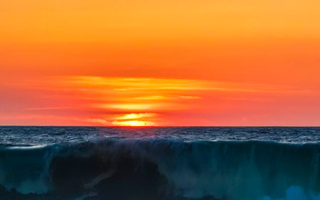 Beautiful stunning colorful and golden sunset in yellow orange red on beach and big wave panorama in...