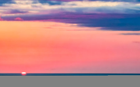 Beautiful stunning colorful and golden sunset in yellow orange red on beach and big wave panorama in tropical nature in Zicatela Puerto Escondido Oaxaca Mexico.の写真素材