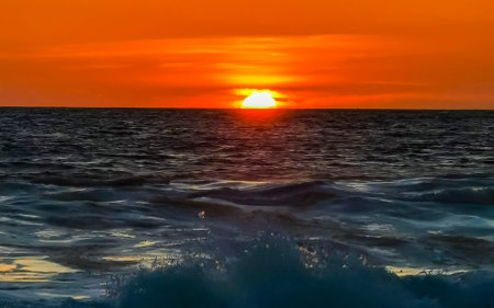 Beautiful stunning colorful and golden sunset in yellow orange red on beach and big wave panorama in tropical nature in Zicatela Puerto Escondido Oaxaca Mexico.の写真素材