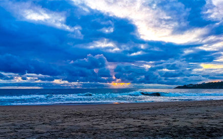 Beautiful stunning colorful and golden sunset in yellow orange red on beach and big wave panorama in tropical nature in Zicatela Puerto Escondido Oaxaca Mexico.の写真素材