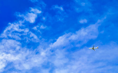 Airplane flying in blue sky with clouds in Playa del Carmen Quintana Roo Mexico.の写真素材