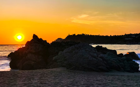Beautiful stunning colorful and golden sunset in yellow orange red on beach and big wave panorama in tropical nature in Zicatela Puerto Escondido Oaxaca Mexico.の写真素材
