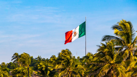 Mexican green white red flag with palm trees and blue sky and clouds in Zicatela Puerto Escondido Oaxaca Mexico.の写真素材