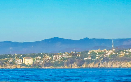 Beach sand blue water rocks cliffs and huge big surfer waves on the beach in Zicatela Puerto Escondido Oaxaca Mexico.の写真素材