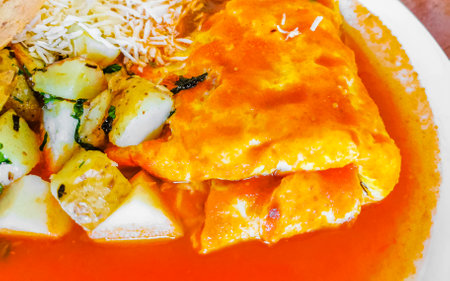 Mexican omelet and scrambled eggs with black beans potatoes and nachos on white plate in El Cafecito...