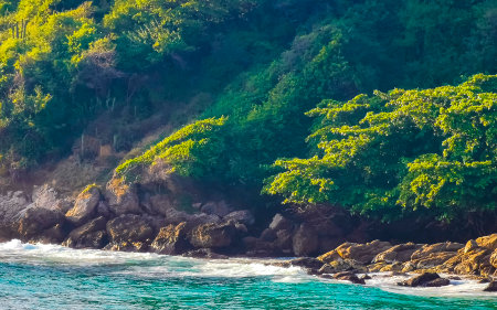 Beach sand turquoise blue water rocks cliffs boulders sun loungers people palm trees and huge big surfer waves on the beach Playa Carrizalillo in Puerto Escondido Oaxaca Mexico.の写真素材