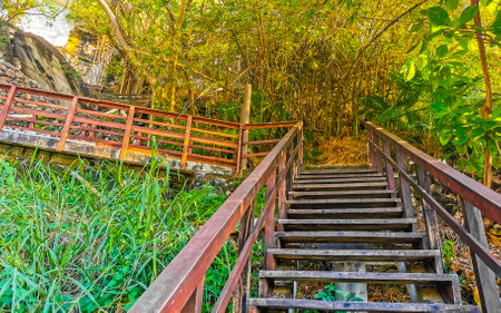 Wooden stairs steps and trail Bto the beach sand turquoise blue water rocks cliffs boulders sun loungers people palm trees and huge big surfer waves on the beach Playa Carrizalillo in Puerto Escondido Oaxaca Mexico.の写真素材