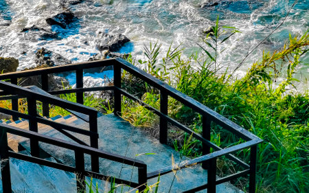 Wooden stairs steps and trail Bto the beach sand turquoise blue water rocks cliffs boulders sun loungers people palm trees and huge big surfer waves on the beach Playa Carrizalillo in Puerto Escondido Oaxaca Mexico.の写真素材