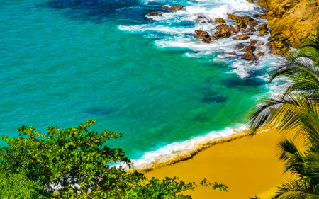 Beach sand turquoise blue water rocks cliffs boulders palm trees huge big surfer waves and panorama view on the beach Playa Carrizalillo in Puerto Escondido Oaxaca Mexico.の写真素材