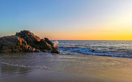 Blue turquoise water and extremely beautiful huge big surfer waves rocks cliffs stones mountains and boulders on the beach in Zicatela Puerto Escondido Oaxaca Mexico.の写真素材