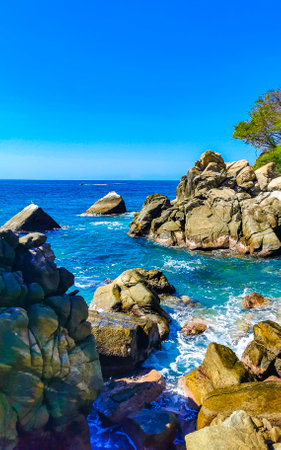 Blue turquoise water and extremely beautiful huge big surfer waves rocks cliffs stones mountains and boulders on the beach in Zicatela Puerto Escondido Oaxaca Mexico.の写真素材