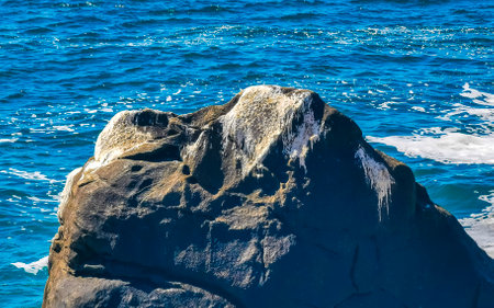 Blue turquoise water and extremely beautiful huge big surfer waves rocks cliffs stones mountains and boulders on the beach in Zicatela Puerto Escondido Oaxaca Mexico.の写真素材