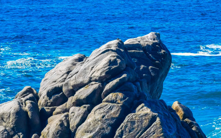 Blue turquoise water and extremely beautiful huge big surfer waves rocks cliffs stones mountains and boulders on the beach in Zicatela Puerto Escondido Oaxaca Mexico.の写真素材
