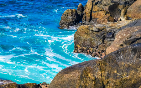 Blue turquoise water and extremely beautiful huge big surfer waves rocks cliffs stones mountains and boulders on the beach in Zicatela Puerto Escondido Oaxaca Mexico.の写真素材