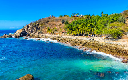 Blue turquoise water and extremely beautiful huge big surfer waves rocks cliffs stones mountains and boulders on the beach in Zicatela Puerto Escondido Oaxaca Mexico.の写真素材
