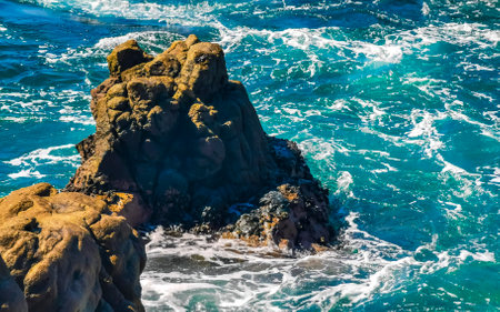 Blue turquoise water and extremely beautiful huge big surfer waves rocks cliffs stones mountains and boulders on the beach in Zicatela Puerto Escondido Oaxaca Mexico.の写真素材