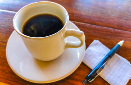 Cup of americano black coffee with with notepad and pen on table food and drink in the restaurant in Zicatela Puerto Escondido Oaxaca Mexico.の写真素材