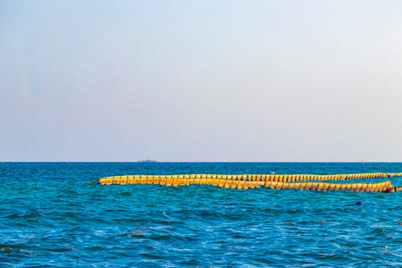 Beautiful blue and turquoise water waves ocean and yellow red orange Buoy buoys ropes and nets in the water of Playa del Carmen in Quintana Roo Mexico.の写真素材