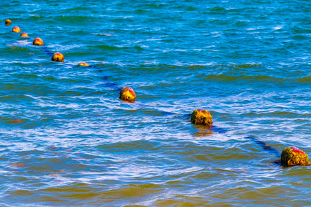 Beautiful blue and turquoise water waves ocean and yellow red orange Buoy buoys ropes and nets in...