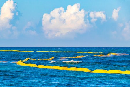 Beautiful blue and turquoise water waves ocean and yellow red orange Buoy buoys ropes and nets in the water of Playa del Carmen in Quintana Roo Mexico.の写真素材