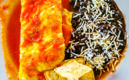 Mexican omelet and scrambled eggs with black beans potatoes and nachos on white plate in El Cafecito in Zicatela Puerto Escondido Oaxaca Mexico.の写真素材