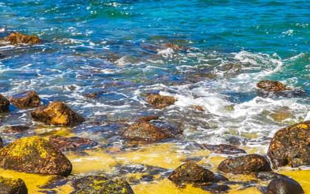 Beach sand turquoise blue water rocks cliffs boulders palm trees huge big surfer waves and panorama view on the beach Playa Manzanillo and Puerto Angelito in Puerto Escondido Oaxaca Mexico.の写真素材