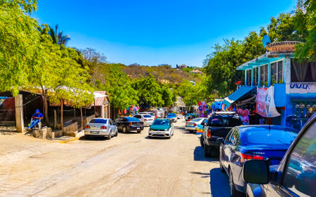 Puerto Escondido Oaxaca Mexico March 25, 2023 Typical beautiful colorful tourist street road and sidewalk with city life cars traffic buildings hotels bars restaurants and people in Zicatela Mexico.のeditorial素材