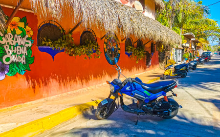 Puerto Escondido Oaxaca Mexico January 27, 2023 Typical beautiful colorful tourist street road and sidewalk with city life cars traffic buildings hotels bars restaurants and people in Zicatela Mexico.のeditorial素材