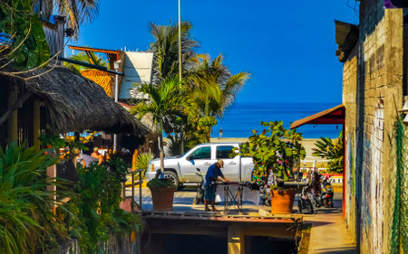 Puerto Escondido Oaxaca Mexico March 29, 2023 Typical beautiful colorful tourist street road and sidewalk with city life cars traffic buildings hotels bars restaurants and people in Zicatela Mexico.のeditorial素材