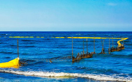 Beautiful blue and turquoise water waves ocean and yellow red orange Buoy buoys ropes and nets in the water of Playa del Carmen in Quintana Roo Mexico.の写真素材