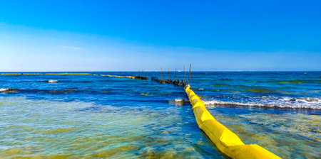 Beautiful blue and turquoise water waves ocean and yellow red orange Buoy buoys ropes and nets in the water of Playa del Carmen in Quintana Roo Mexico.の写真素材