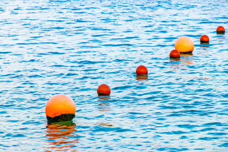 Beautiful blue and turquoise water waves ocean and yellow red orange Buoy buoys ropes and nets in...
