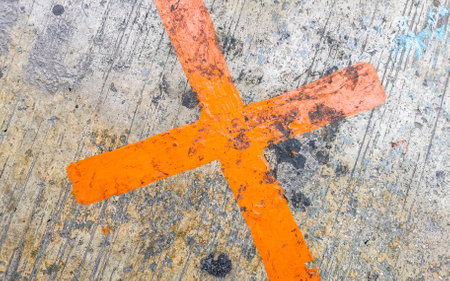 Orange painted cross on the sidewalk in Playa del Carmen Quintana Roo Mexico.
