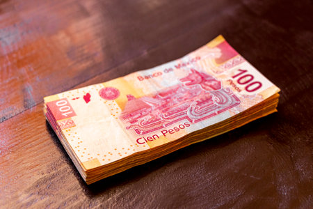 Playa del Carmen Quintana Roo Mexico February 22, 2021 Stack of banknotes 100 Mexican pesos on a wooden table in Playa del Carmen Quintana Roo Mexico.のeditorial素材
