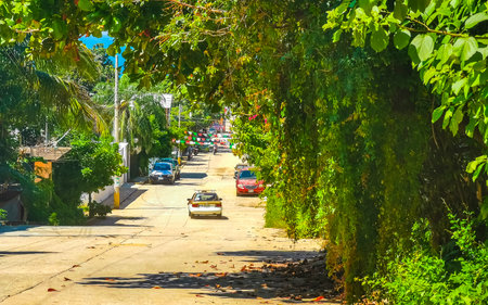 Puerto Escondido Oaxaca Mexico October 03, 2022 Typical beautiful colorful tourist street road and sidewalk with city life cars traffic buildings hotels bars restaurants and people in Zicatela Mexico.のeditorial素材