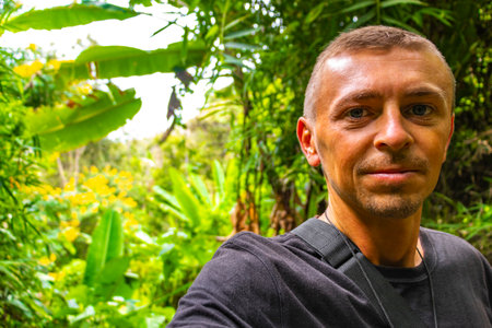 Handsome male tourist man at tropical jungle and forest hiking trails through nature to the mountain...