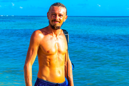 Male tourist traveling man with long hair is posing for a photo model and having fun swim on the Mexican Caribbean beach in Playa del Carmen Quintana Roo Mexico.の写真素材